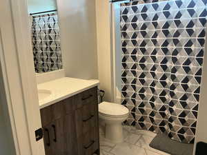 Full bath featuring vanity, a shower with curtain, and light marble finish floors