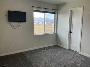 Unfurnished bedroom featuring dark carpet and baseboards