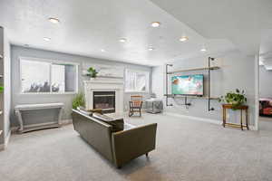 Living room with carpet floors, a textured ceiling, a glass covered fireplace, and recessed lighting