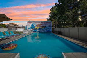 Pool at dusk featuring a fenced backyard and a patio area