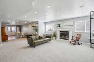 Carpeted living area with a textured ceiling, recessed lighting, and a glass covered fireplace