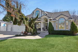 View of front of house with a front lawn, roof with shingles, stucco siding, and driveway
