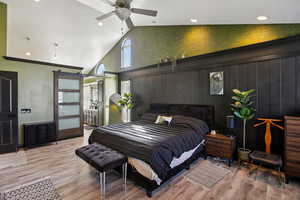 Bedroom featuring a barn door, recessed lighting, light wood-style flooring, a high ceiling, and access to outside