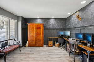 Office with recessed lighting, light wood-style floors, wallpapered walls, and a wainscoted wall