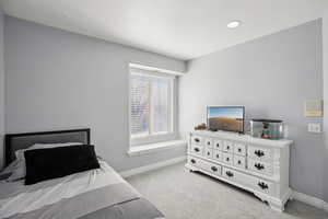 Bedroom featuring light carpet and baseboards