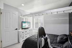Bedroom featuring light colored carpet and a textured ceiling