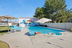 View of swimming pool featuring patio surround and a fenced backyard