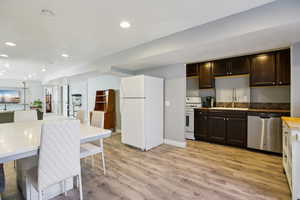 Kitchen featuring white appliances, open floor plan, butcher block countertops, recessed lighting, and light wood-style flooring