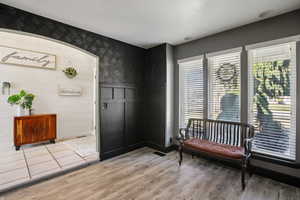 Living area with light wood-style floors, wallpapered walls, and a wainscoted wall