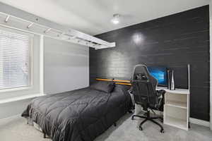 Carpeted bedroom featuring wood walls and a desk