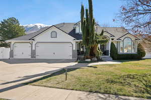 View of front of property featuring a front lawn, brick siding, an attached garage, and driveway
