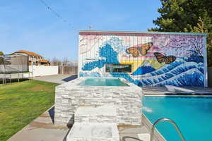 Outdoor pool with a trampoline, an outdoor hot tub, a patio, and a fenced backyard