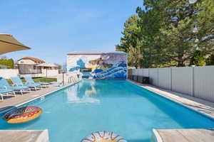 View of pool with a fenced backyard, patio surround, and a trampoline