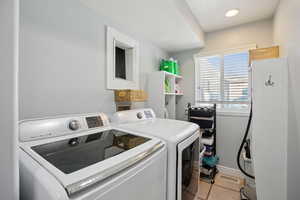 Laundry area with light tile patterned floors and washing machine and dryer