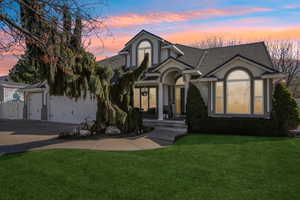View of front of property featuring a front lawn, stucco siding, roof with shingles, driveway, and an attached garage