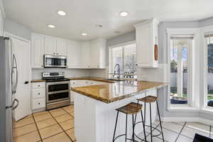 Kitchen with stainless steel appliances, white cabinets, a peninsula, and recessed lighting