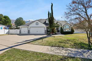 View of front facade with a gate, a garage, driveway, a front lawn, and stucco siding