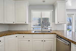 Kitchen featuring white cabinets, dishwasher, and dark stone counters