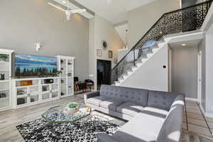 Living room with a high ceiling, light wood-style floors, and ceiling fan