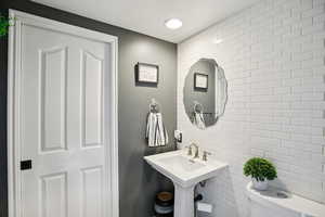 Half bath featuring tile walls and recessed lighting