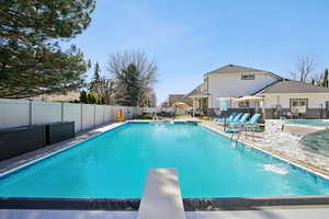 View of swimming pool with patio surround, a diving board, and a fenced backyard