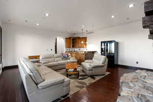 Living area featuring arched walkways, recessed lighting, and dark wood-style floors