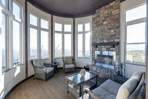 Living area with a fireplace, a high wooden ceiling, healthy amount of natural light, and carpet