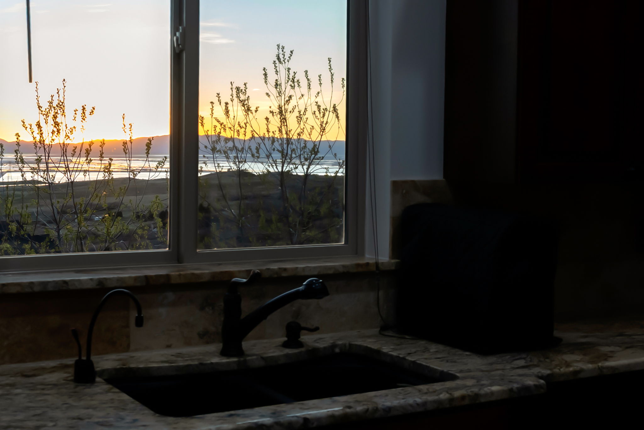 Kitchen view of light stone counters and mountains