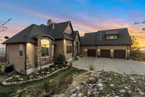 View of front facade featuring stucco siding, stone siding, concrete driveway, and a chimney