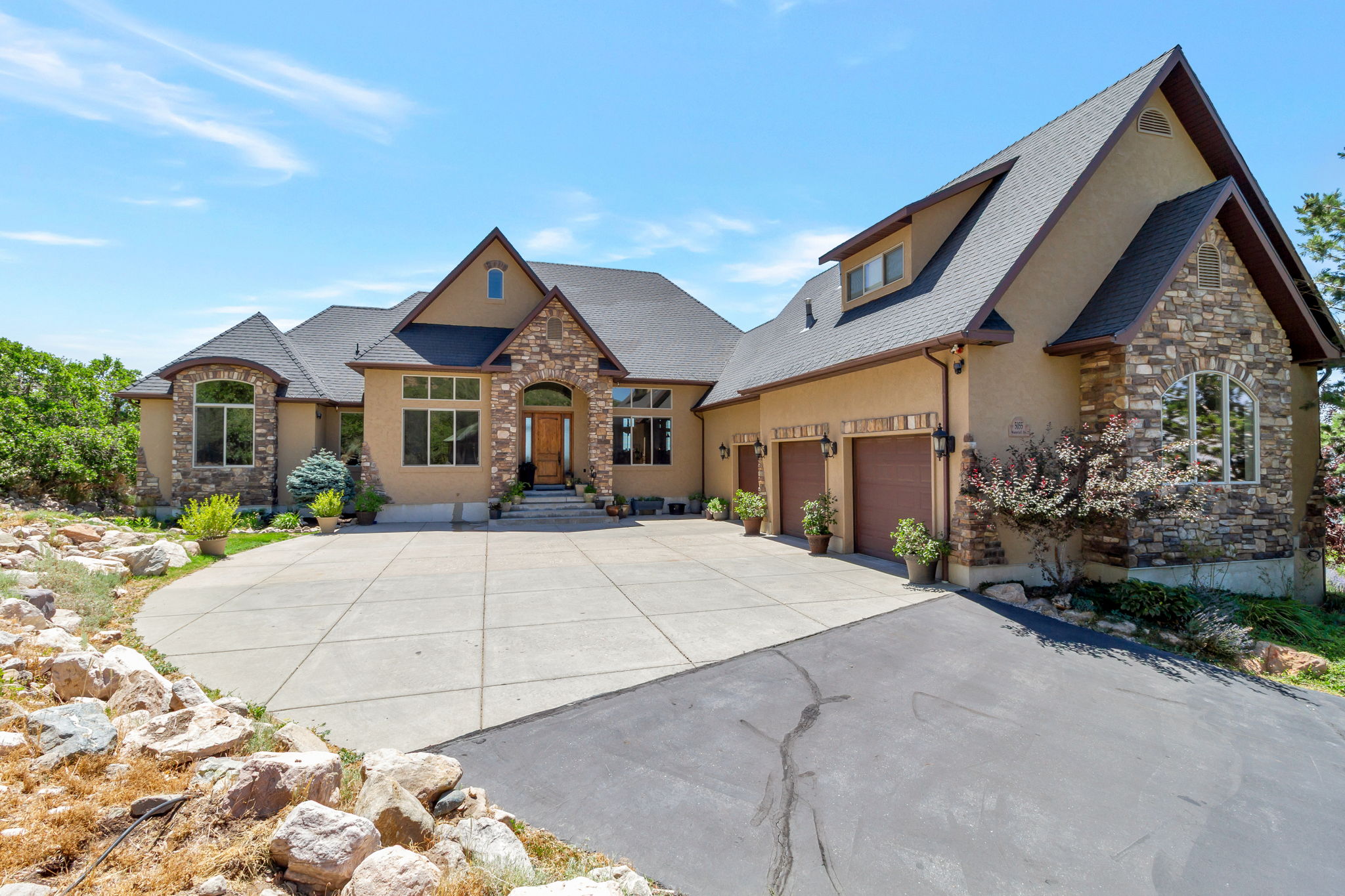 Stucco exterior with stone accents and a dark shingle roof