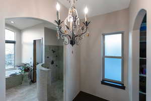 Bathroom featuring a walk in shower, a garden tub, and hanging lights