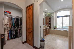 Bathroom with vanity, recessed lighting, a garden tub, a barrel ceiling, and a walk in closet