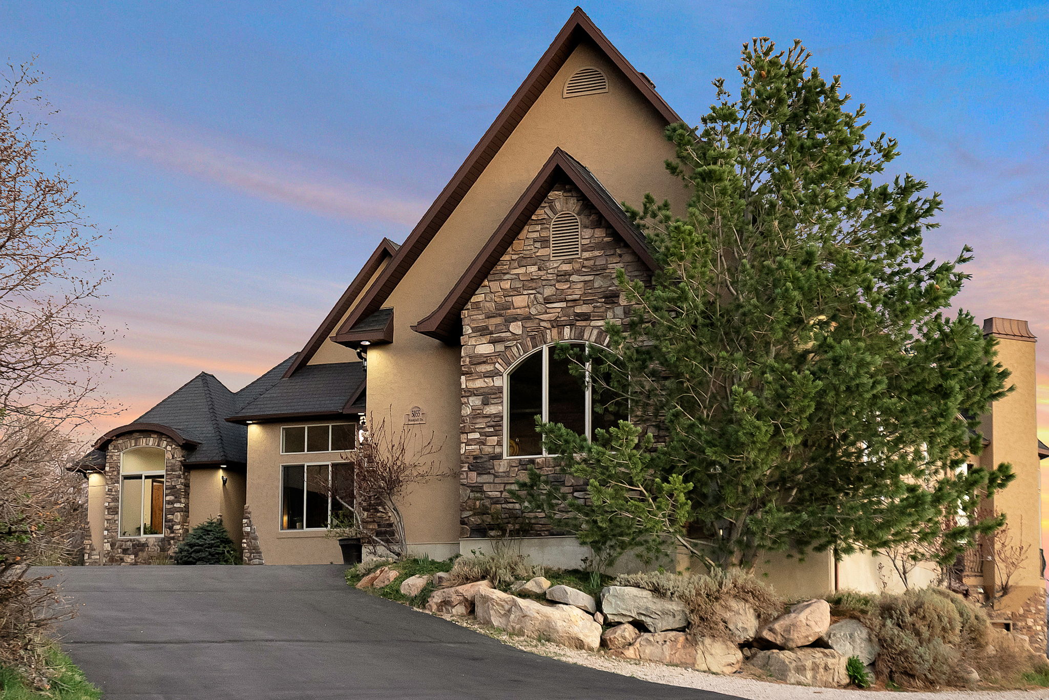 View of front facade featuring stone siding and stucco siding