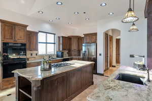 Kitchen with arched walkways, a kitchen island, open shelves, tasteful backsplash, and dark wood finish cabinetry