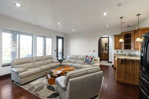 Living room featuring arched walkways, dark wood-style floors, and recessed lighting