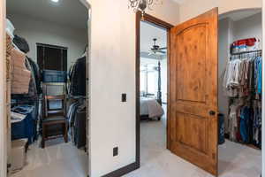 Walk in closet featuring light carpet, arched walkways, and ceiling fan
