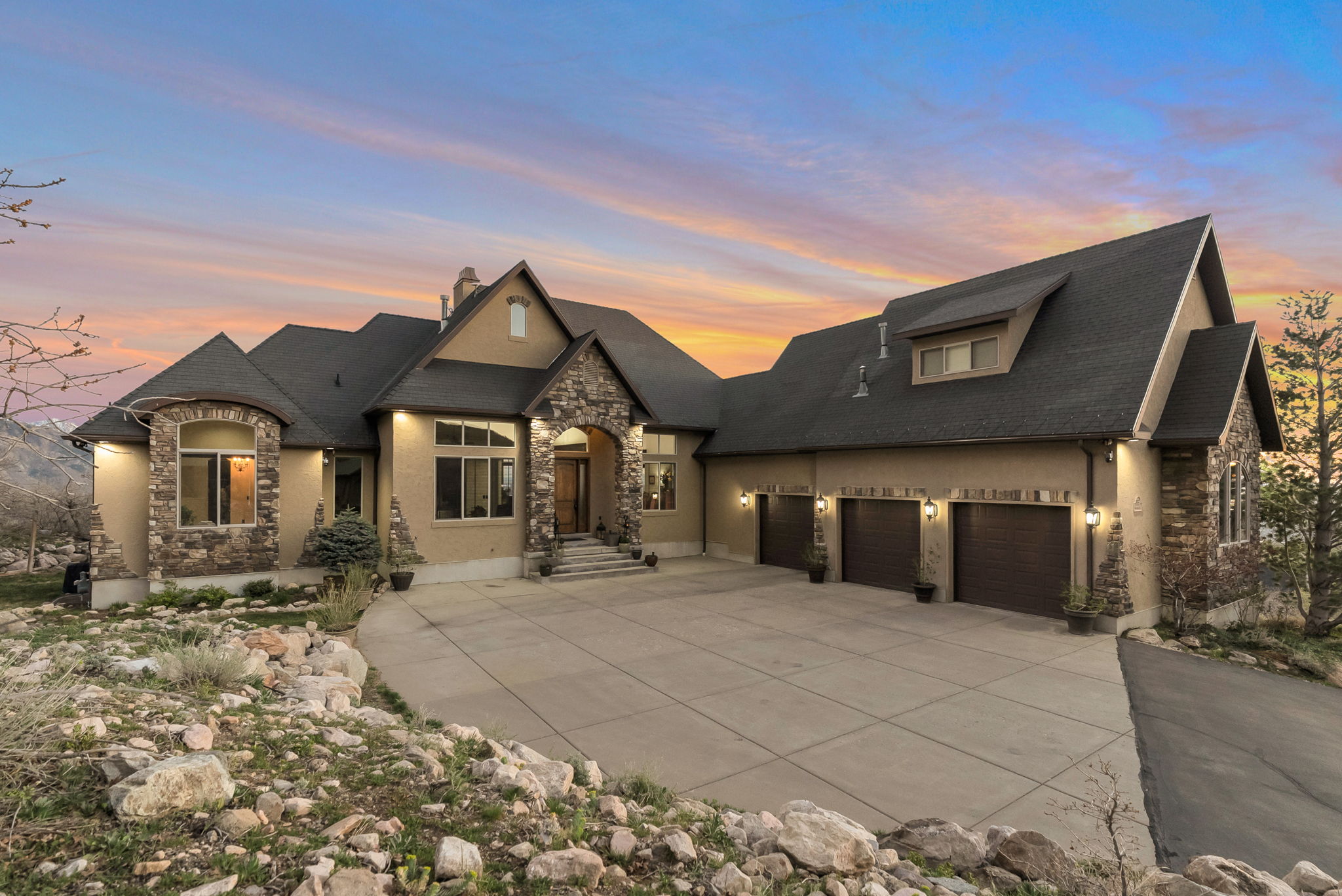 French country inspired facade with stone siding, an attached garage, concrete driveway, and a chimney