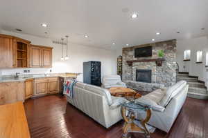Living area featuring recessed lighting, dark wood-type flooring, and a stone fireplace