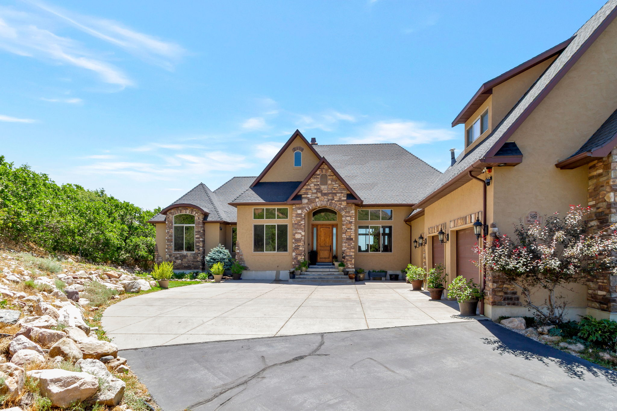 Stucco exterior with stone accents and a dark shingle roof