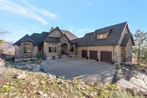 French provincial home with stone siding, a garage, driveway, a chimney, and stucco siding