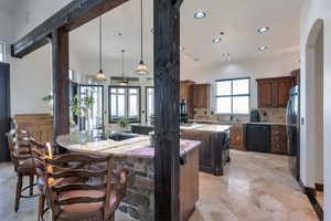 Kitchen with tasteful backsplash, dishwasher, freestanding refrigerator, and light stone countertops