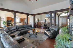 Living room featuring dark wood-style flooring, lofted ceiling, a ceiling fan, arched walkways, and suspended lighting