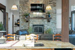 Living area featuring a stone fireplace and a high ceiling