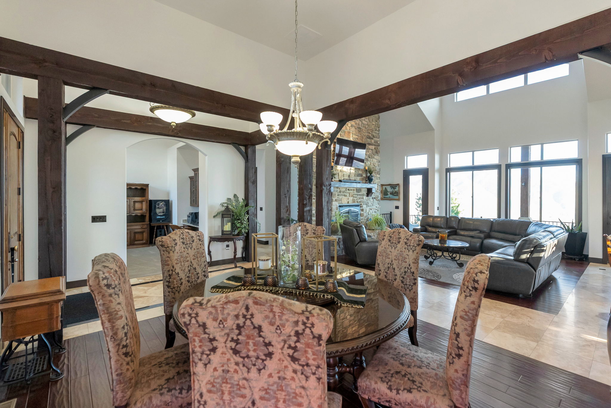 Dining space with suspended lighting, arched walkways, wood-type flooring, a fireplace, and a high ceiling