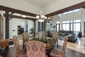 Dining space with suspended lighting, arched walkways, wood-type flooring, a fireplace, and a high ceiling