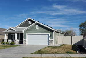 Craftsman house featuring a gate, an attached garage, stone siding, concrete driveway, and covered porch