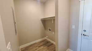 Laundry area featuring light wood-style flooring, washer hookup, and electric panel