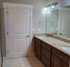 Bathroom with double vanity and light tile patterned floors