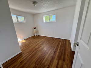 Unfurnished bedroom with dark wood-style floors and a textured ceiling