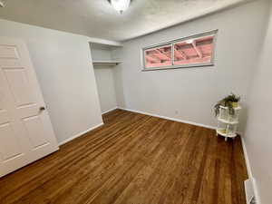 Unfurnished bedroom with a textured ceiling, a closet, and dark wood-style floors
